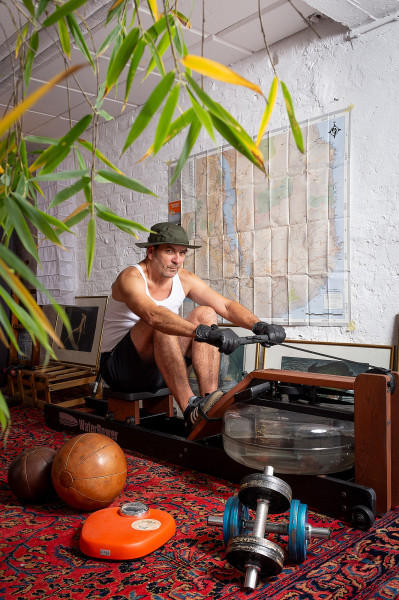 Sportiver Senior im Keller auf Rudermaschine im filmischen Licht.